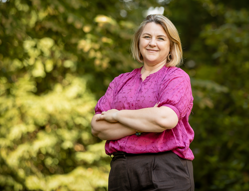 Bettina steht selbstbewusst im Wald